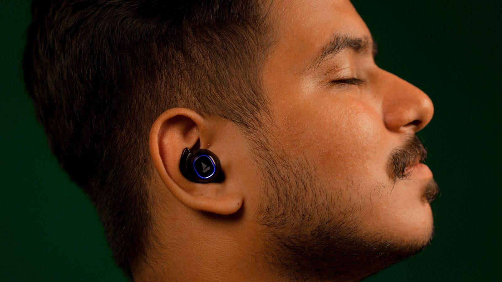 Man listening to music with wireless earbuds with a calm expression