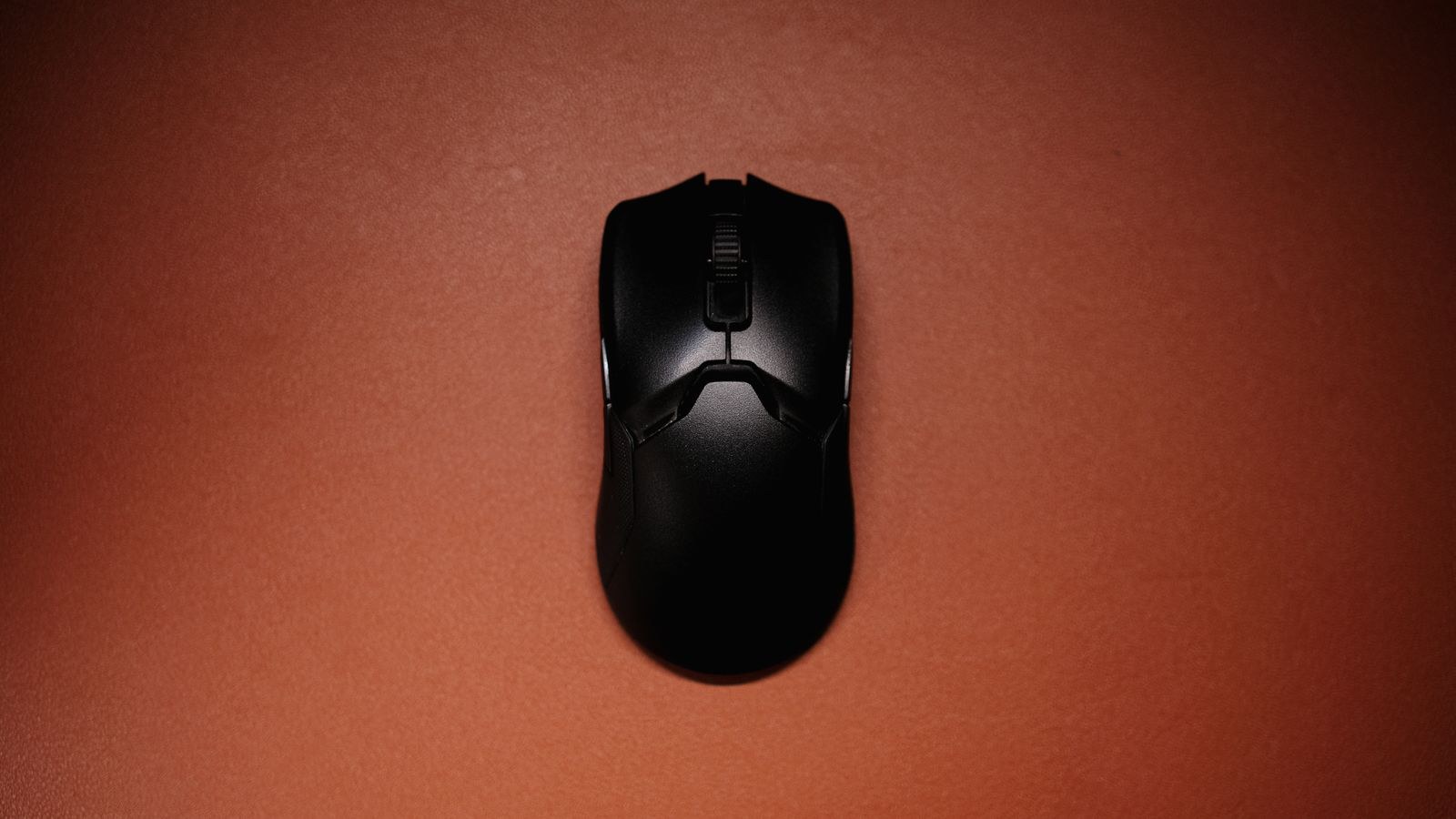 Top view of a sleek black wireless mouse on a red background