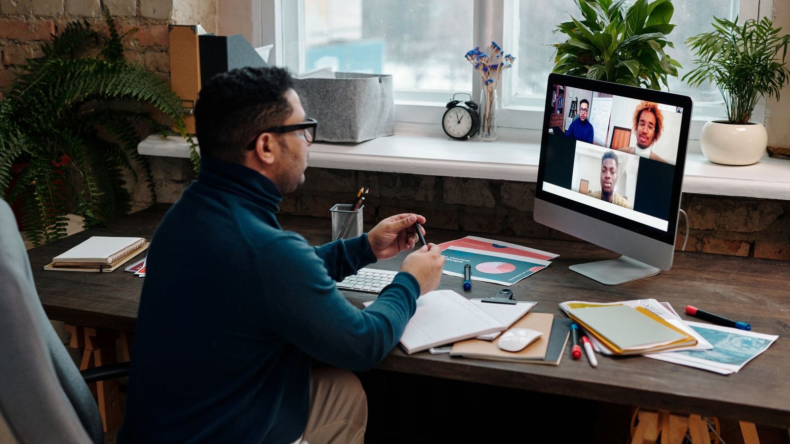 Man working remotely from a home office desk with headset and laptop